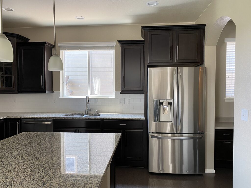 Espresso brown kitchen with granite counters and large kitchen island and fridge